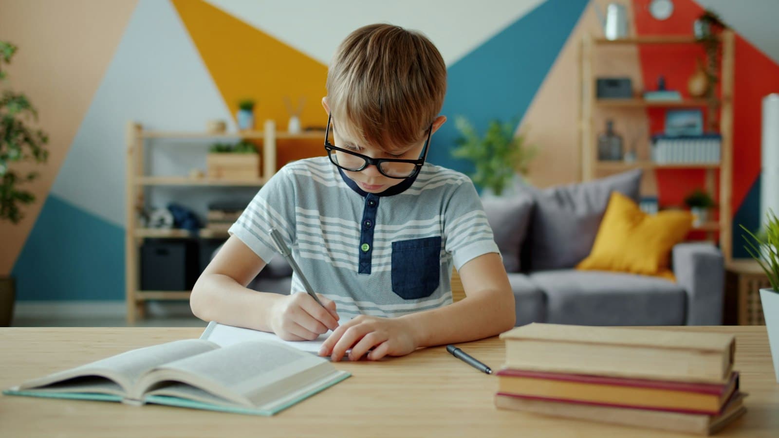 A boy with glasses doing homework at a desk
